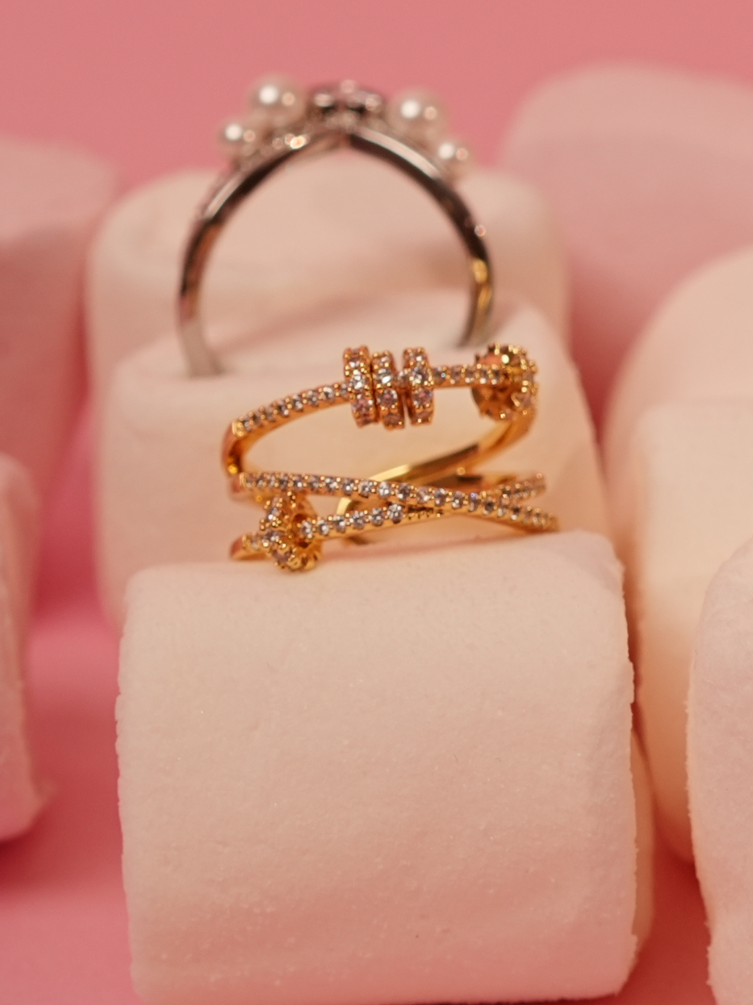 Gold ring with diamond accents on a pink background